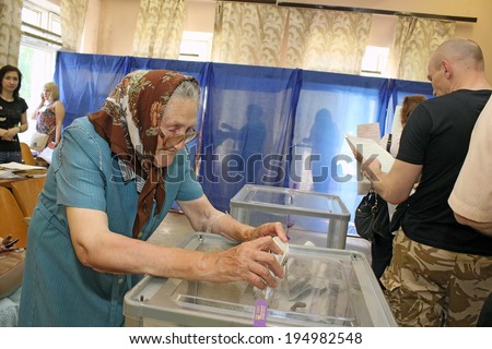 Kiev, Ukraine - May 25, 2014: Election of the President of Ukraine and Kiev measure. Mature woman throws her bulletin in the ballot box.