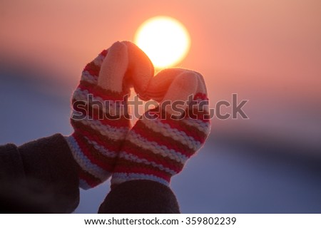 Woman hands in winter gloves Heart symbol shaped Lifestyle and Feelings concept with sunset light nature on background