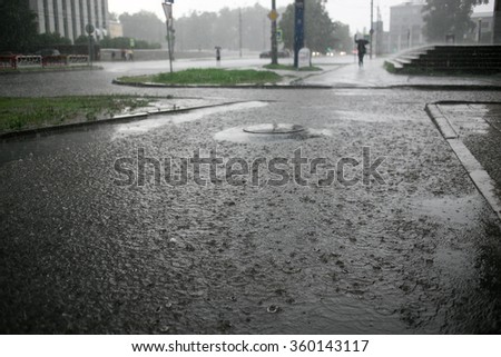 heavy rain drops falling on city street during downpour