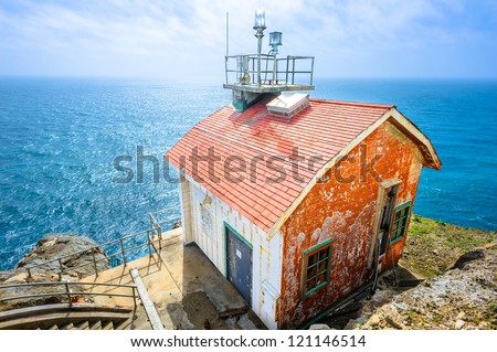 Old colorful beautiful house on the edge of the earth and the deep blue ocean behind.