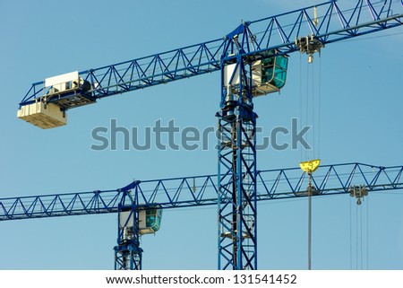 Two hoisting cranes and blue sky
