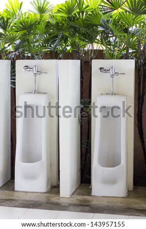 White porcelain male urinal in the green environment