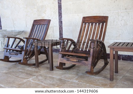Two wooden rocking chairs with small tables