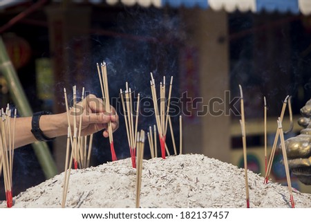 Hand placing incense sticks in the pot