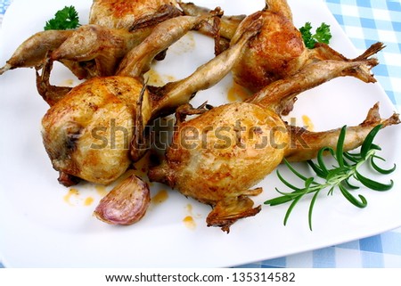 Four fried quail with gravy, garlic and rosemary, top view