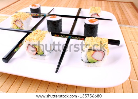 Play tic tac toe with sushi and black chopsticks, close up