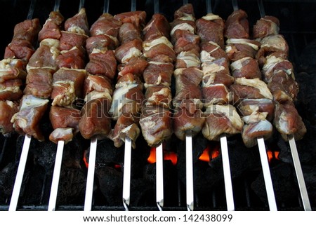Marinated shashlik, raw lamb meat grilling on metal skewer, close up