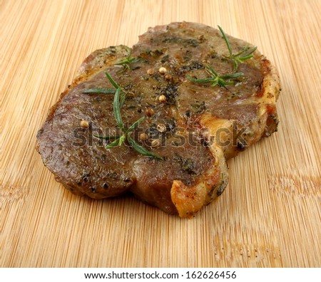 Grilled neck steak marinated in herbs at bamboo background, close up