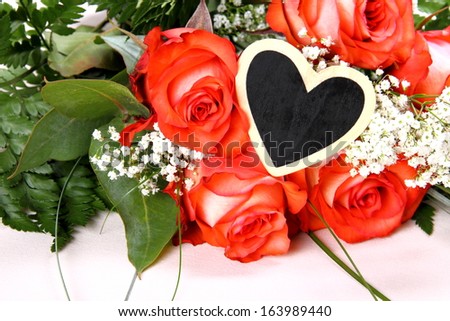 Red roses with writing board in heart shape, close up
