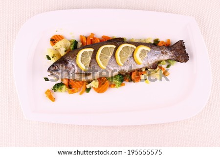 Grilled whole trout with vegetables and lemon, top view
