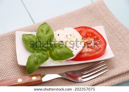 Basil leaf, mozzarella cheese, tomato slice, fork, top view