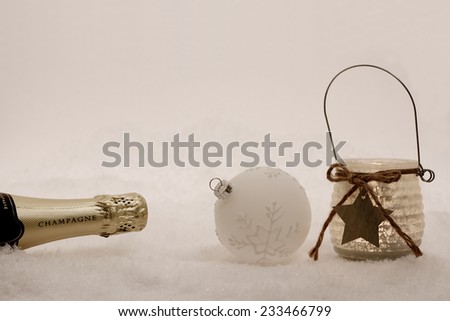 Christmas ball,  wind candle, champagne bottle in snow, evening