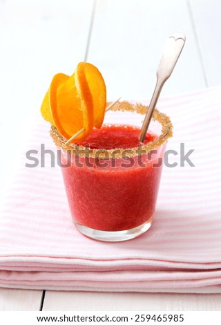 Strawberry smoothie topped with brown sugar, orange slice, close up
