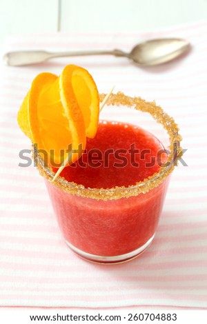 Strawberry smoothie topped with brown sugar, orange slice, top view