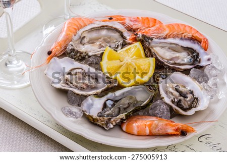 oysters shell, jumbo shrimp with lemon on ice, top view