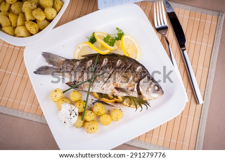 Grilled carp fish with rosemary potatoes and lemon, top view