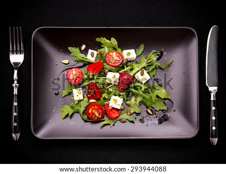 Strawberry tomato salad with feta cheese, olive oil and cutlery top view