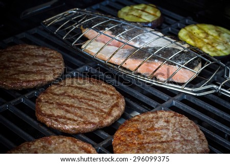 Hamburger slices, salmon steak and eggplant on grill rack, soft focus