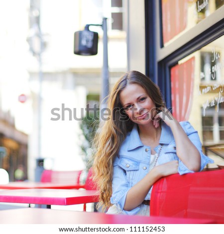 beautiful young woman sitting alone in street cafe