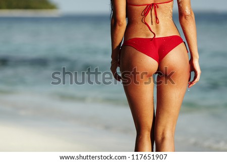 Sexy back of a beautiful woman in red bikini on sea background