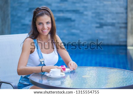 Happy young girl in summer outdoor cafe with coffee and cake