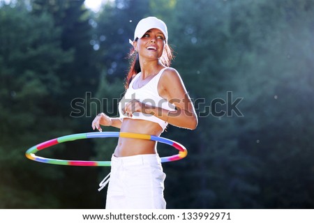 woman rotates hula hoop on nature background
