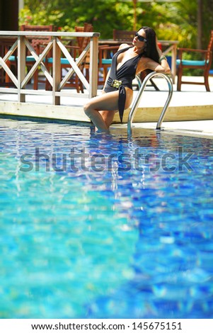 Beautiful woman posing on stairs of swimming pool