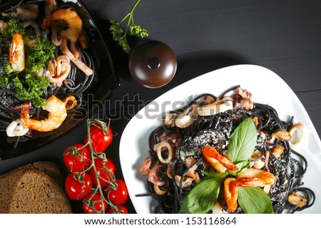 Black spaghetti with seafood on black table