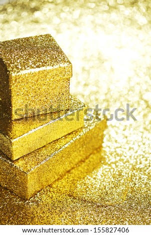 Golden boxes with holiday gifts on shiny glitter background