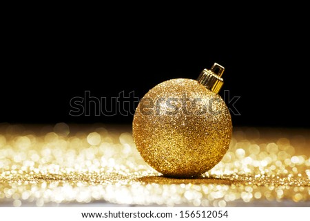 Golden christmas ball on glitter background with black copy space