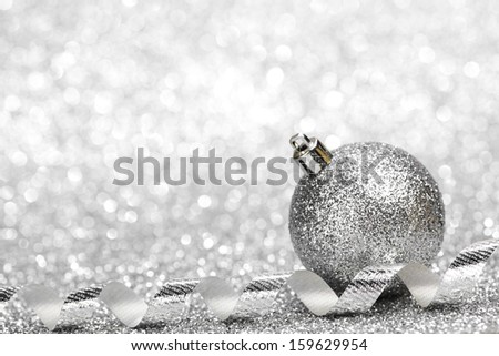 Silver Christmas decoration ball and ribbon on glitter background
