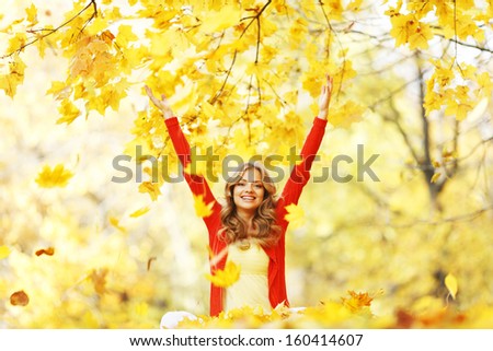 Happy woman in autumn park drop up leaves