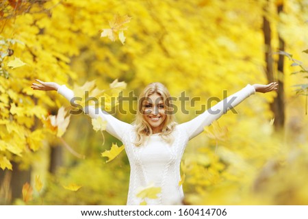 Happy woman drop up leaves in autumn park