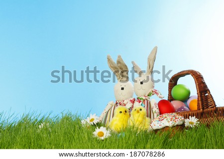 Easter card with eggs in basket and toy rabbits on green grass