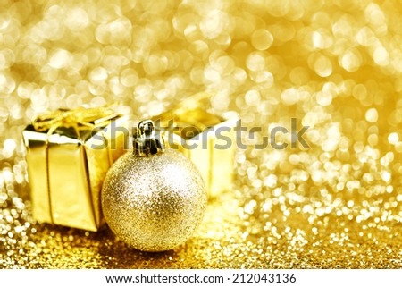 Golden Christmas ball and gifts on abstract glitter background