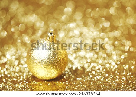 Golden christmas ball on shining glitter background close-up
