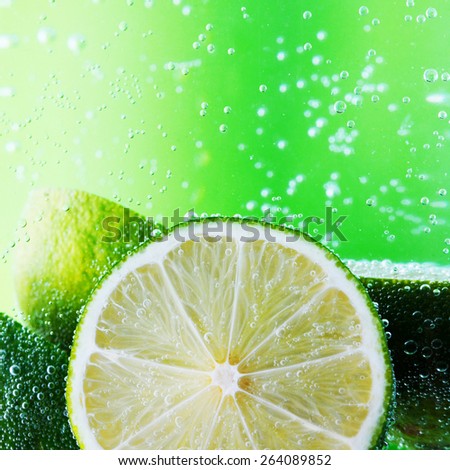 Cut limes in the water with bubbles on green background