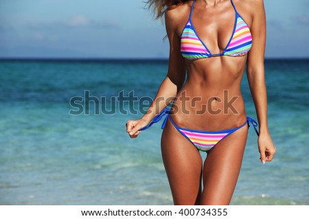 Woman with perfect body in bikini over blue sea background