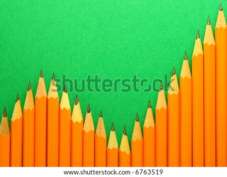a bar graph of increasing trend formed by yellow pencils on a green background