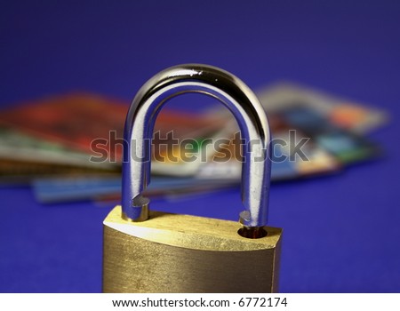 a close up on a padlock, several credit cards on the background. Shallow depth of field, focus on the padlock being unlocked