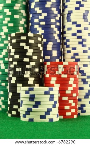 A close up on several stacks of gambling chips over a green table, viewed from the table level