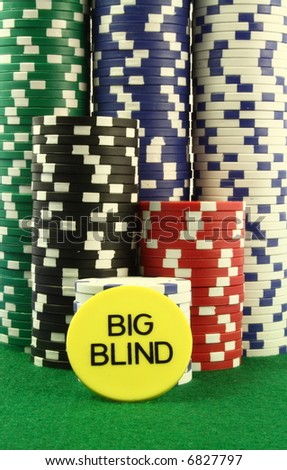 Big blind chip in front of several piles of poker chips on a green table. View from the table level