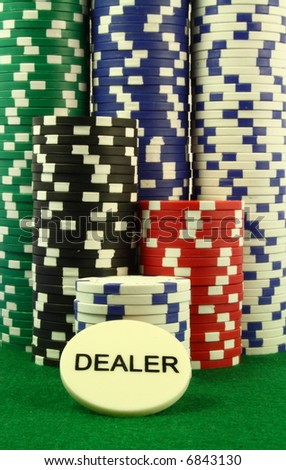 a dealer chip in  front of several piles of poker chips on a green table.