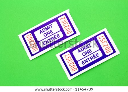 a pair of blue admit one tickets over a green surface