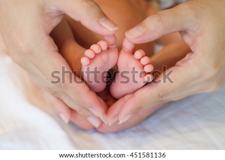baby boy feet on his mom hand,hold on heart sign on natural light