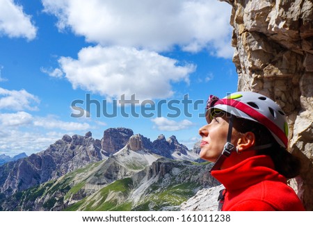Portrait of happy female climber with helmet and headlamp looking up. Dolomites, Italy.