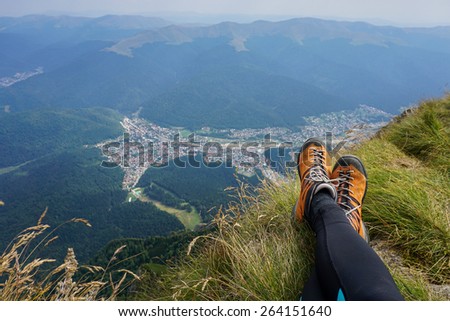 Legs of a woman sitting on the edge n the beautiful mountains of Romania