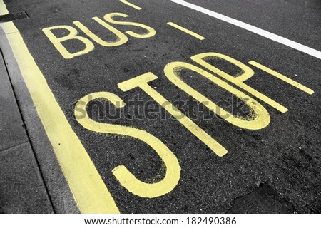 Bus stop sign with yellow paint on asphalt