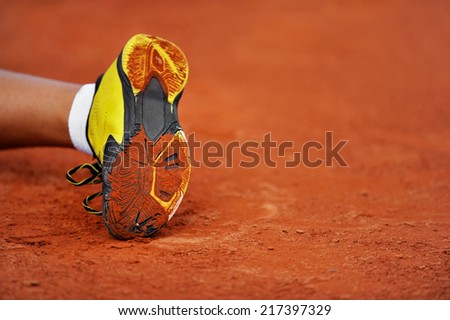 Detail with a tennis shoe sole on a tennis clay court