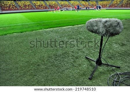 Professional sport microphone on a football field with players training in the background